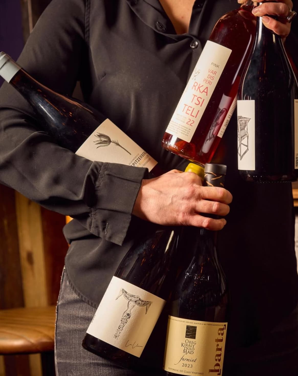 A member of staff at The Lady of the Grapes holding an armful of natural wine bottles