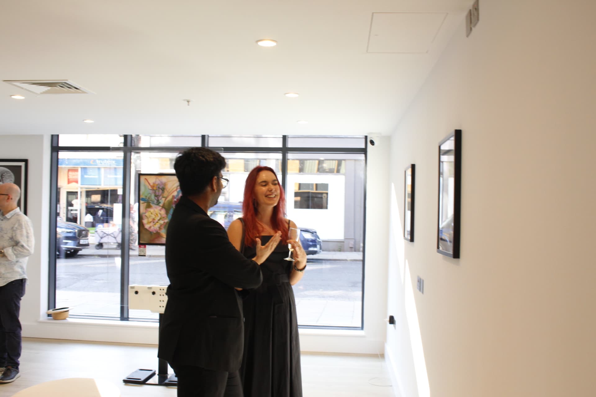 Artist speaking with a visitor at a gallery opening while selling art in person