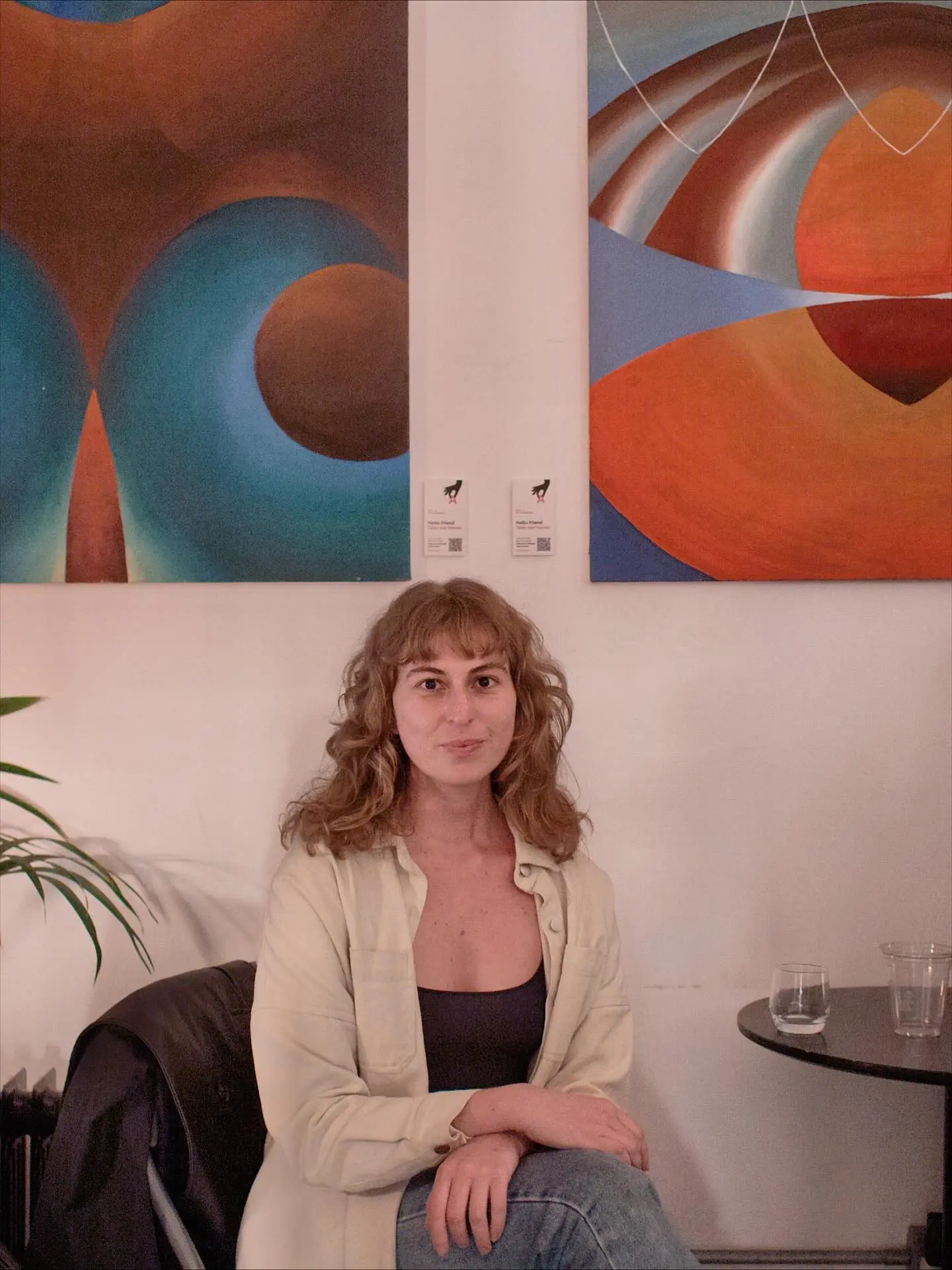 Libby Hoffenberg seated alongside her paintings placed via PickArt consignment at Sevente, London