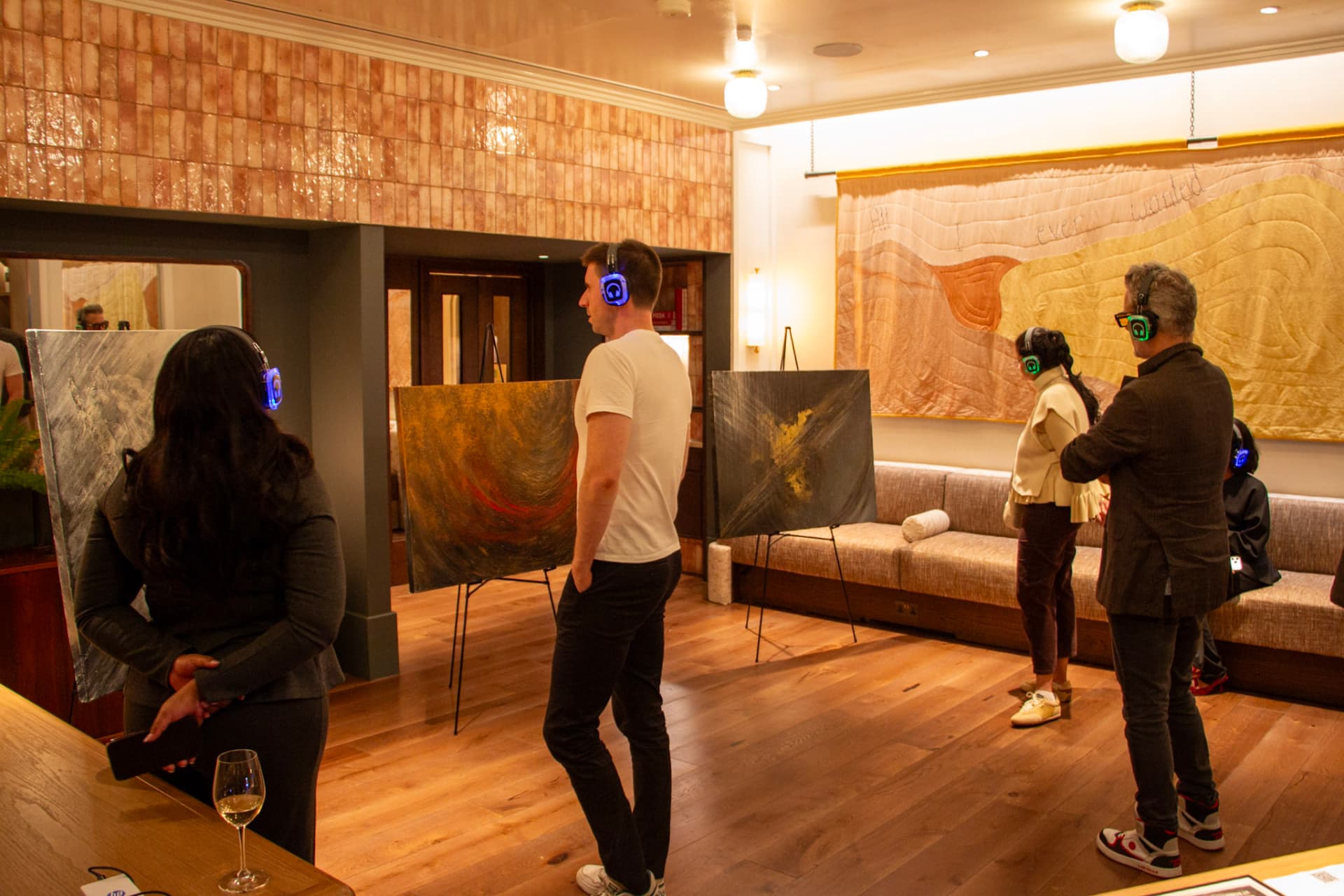 Guests in headphones listening in front of paintings at Maslow's Kensington